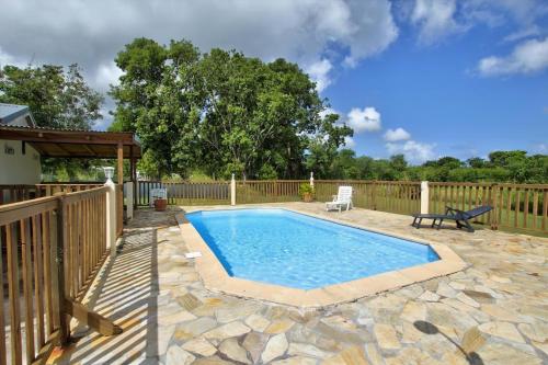 a swimming pool on a patio with a wooden fence at Domaine De Berard in Sainte-Anne