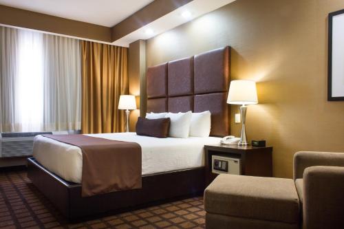 a hotel room with a bed and a chair at Best Western PREMIER Monterrey Aeropuerto in Monterrey