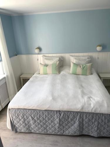 a bedroom with a white bed with green and white pillows at Egn Boutique Hotel in Stege