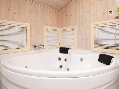 een badkamer met een wit bad en 2 ramen bij 8 person holiday home in Humble in Humble