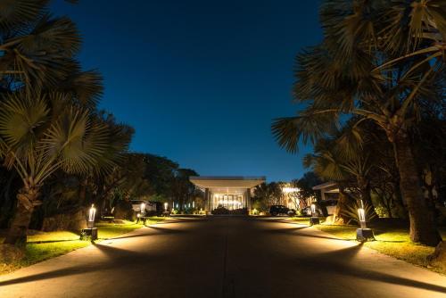 a street with palm trees and a building at night at Hyatt Hyderabad Gachibowli in Hyderabad