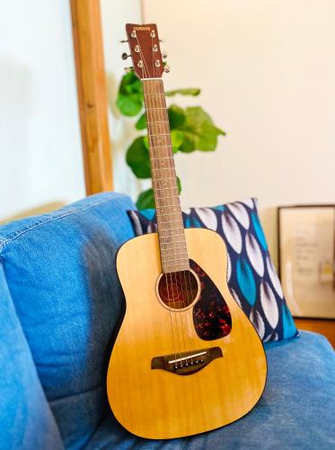 a guitar sitting on top of a blue couch at TABISAI HOTEL House 博多 in Fukuoka