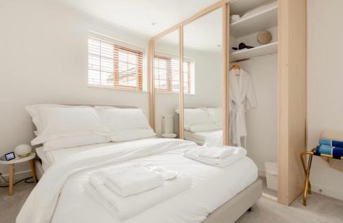 a white bedroom with a large white bed and a mirror at Rose Mews Central Broadstairs in Kent