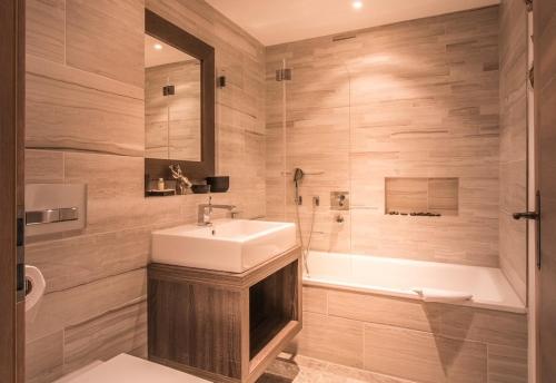 a bathroom with a sink and a bath tub at Bergwelt Grindelwald Residence in Grindelwald