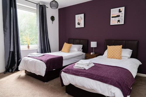 two beds in a room with purple walls and a window at Wingfield Lodge - Near Clay Cross in Chesterfield