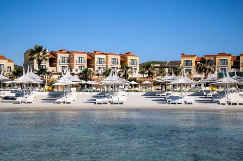 a beach with chairs and umbrellas on the beach at Cocos The Club Solto in Alaçatı