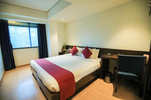 a hotel room with a bed and a desk and a window at Hotel German Palace Near to Airport in Gandhinagar