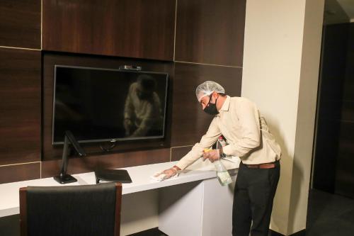 a man standing next to a desk with a tv at Hotel German Palace Near to Airport in Gandhinagar
