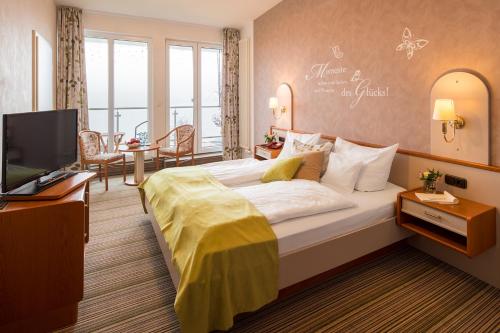 ein Hotelzimmer mit einem großen Bett und einem TV in der Unterkunft PlusNaturHotel direkt am Ederseeufer Waldhotel Wiesemann und Ferienapartments in Waldeck