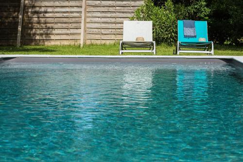 2 chaises assises à côté d'une piscine d'eau dans l'établissement Au Coeur des Eléments, à Saint-Nicolas-de-la-Grave