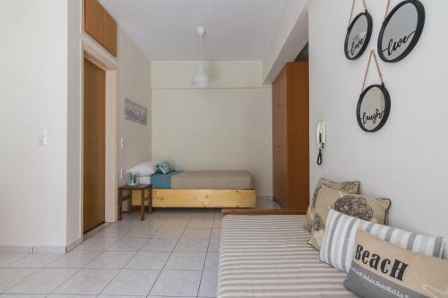 a living room with a bed and clocks on the wall at Homey Studio for 3 ppl in Heraklion City in Néa Alikarnassós