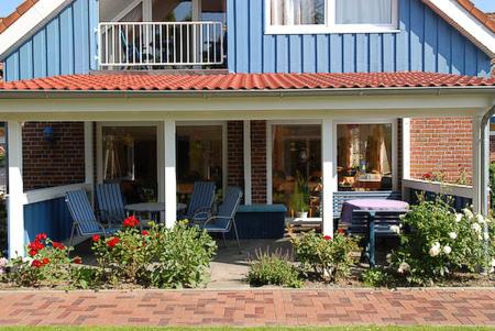 a blue house with chairs and a table on a patio at Hotel-Pension Altes Siel in Bensersiel