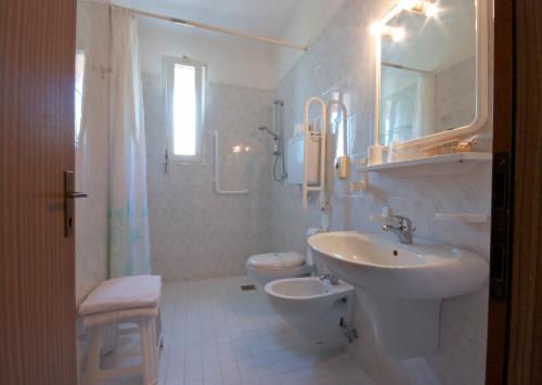 a white bathroom with a sink and a toilet at Hotel Toledo in Lido di Jesolo