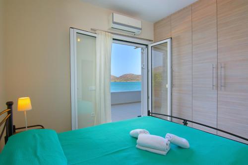 - une chambre avec un lit vert et une vue sur l'océan dans l'établissement Kristallia - Elounda seafront vacation rental, à Elounda