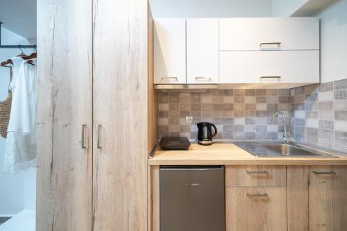 a kitchen with wooden cabinets and a sink at Aquamarine Luxury Rooms Thassos in Limenas