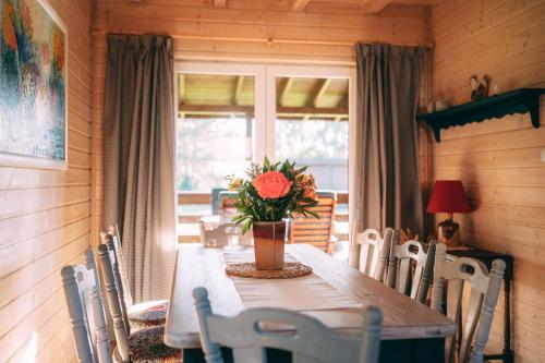 a dining room with a table with a vase of flowers on it at Łap Las Pelnik in Pelnik