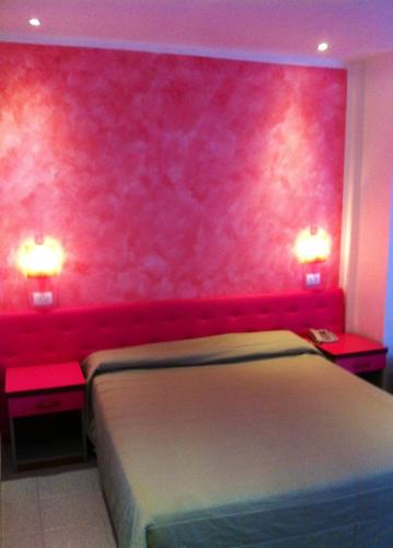 a bedroom with a pink wall with a bed and two tables at Bellevue del Golfo Hotel & Spa in Sferracavallo