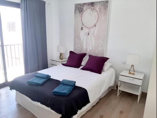 Un dormitorio con una cama grande con almohadas moradas. en Casa Diana, en Playa Honda