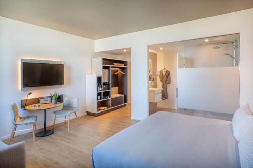 a bedroom with a bed and a table and a bathroom at INNSiDE by Meliá Luxembourg in Luxembourg