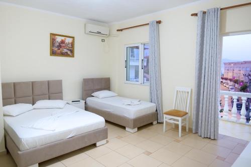 1 dormitorio con 2 camas y ventana en Hotel Rixhi, en Sarandë