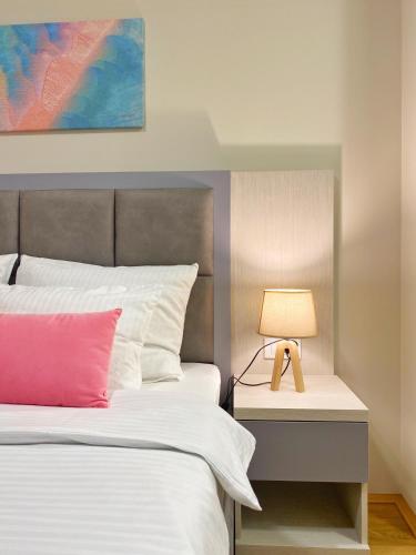 a bedroom with a bed and a lamp on a nightstand at Hotel Olimpija plus in Herceg-Novi