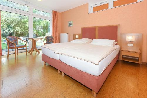 a bedroom with a large bed and a table and chairs at Hotel-Pension Altes Siel in Bensersiel