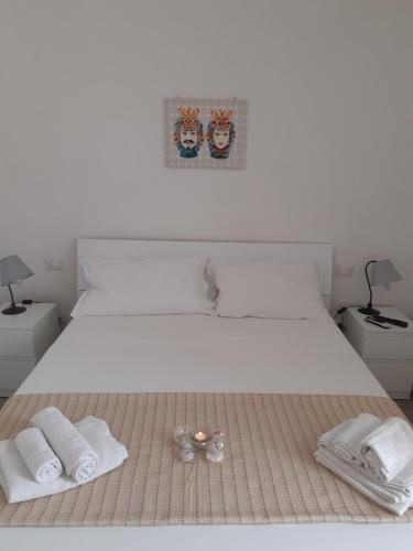 a white bed with two towels and two glasses on it at Fronte Mare in Avola