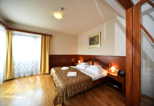 a hotel room with a bed and a window at Hotel Kumánia in Kisújszállás