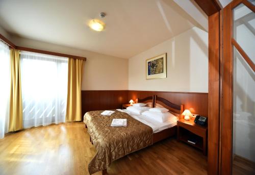pokój hotelowy z łóżkiem i oknem w obiekcie Hotel Kumánia w mieście Kisújszállás