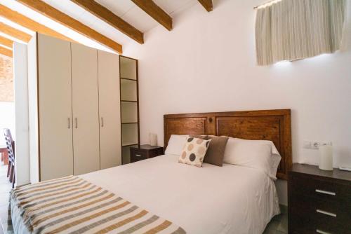 Un dormitorio con una cama blanca con cabecero de madera. en Agroturismo Sa Canoveta, en Colonia de Sant Jordi