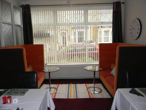Cette chambre dispose de deux chaises orange et d'une grande fenêtre. dans l'établissement Devon Guest House, à Blackpool