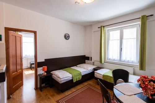 Habitación pequeña con cama, mesa, mesa y sillas. en Hello Apartmanház, en Sopron