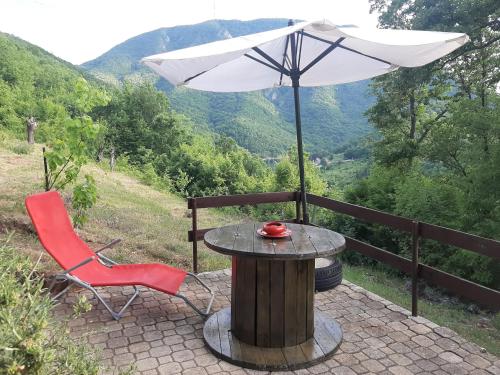 a table with an umbrella and a red chair at Vila Eva in Međuvršje