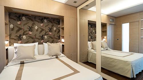 1 Schlafzimmer mit 2 Betten und einem Spiegel in der Unterkunft Hotel Estense in Gatteo a Mare