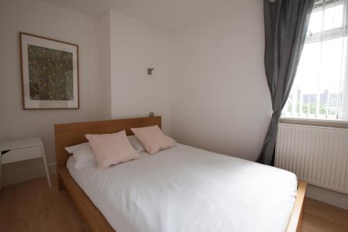 a bedroom with a bed with two pillows and a window at Tooting Rooms & Studio by PrimeCityHosts in London