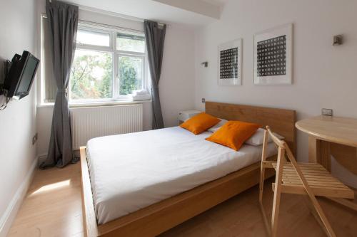 a bedroom with a bed with orange pillows on it at Tooting Rooms & Studio by PrimeCityHosts in London