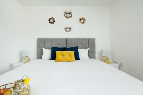 a bedroom with a large bed with blue and yellow pillows at KVM - Thorpe House close to town by KVM Stays in Peterborough