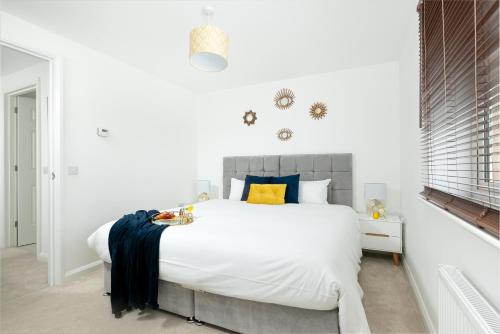 a white bedroom with a large white bed with blue and yellow pillows at KVM - Thorpe House close to town by KVM Serviced Accommodation in Peterborough