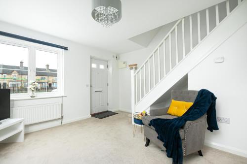 a living room with a chair with a yellow pillow at KVM - Thorpe House close to town by KVM Stays in Peterborough