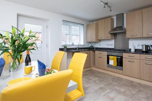 a kitchen with yellow chairs and a dining table at KVM - Thorpe House in Peterborough