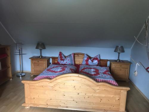 a bedroom with a wooden bed with two pillows at Ferienwohnung am Hochrhöner in Andenhausen