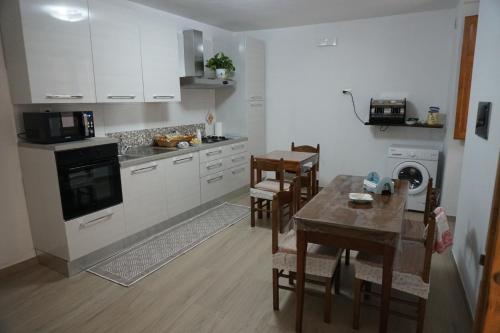 kuchnia z białymi szafkami, stołem i krzesłami w obiekcie Casa Vacanze B&B Ondes w mieście Camerota