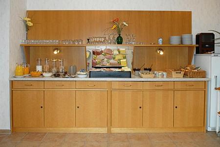 a kitchen with wooden cabinets and a counter top at Hotel-Pension Altes Siel in Bensersiel