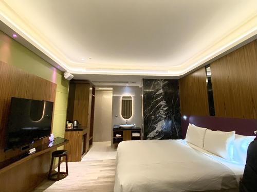 a hotel room with a bed and a flat screen tv at LE LE Motel in Pingtung City