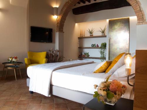 a bedroom with a large white bed and yellow chairs at La Corte Segreta in Montepulciano