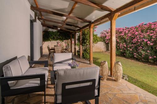 a patio with chairs and a pergola with pink flowers at Allegra Villa in Kipseli