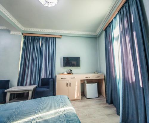 a bedroom with a bed and a desk and curtains at MUSMORE Boutique Hotel in Tbilisi City