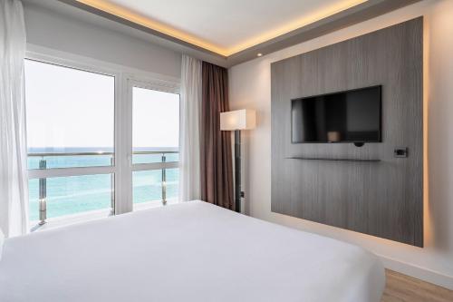 a bedroom with a white bed and a television at Melia Alicante in Alicante