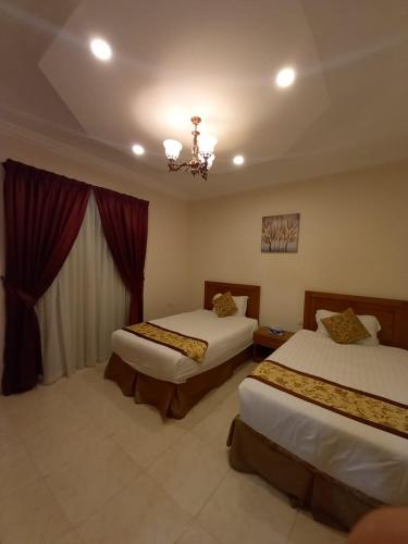a hotel room with two beds and a chandelier at سارة للشقق المخدومة Sara Serviced Apartments in Al Khobar