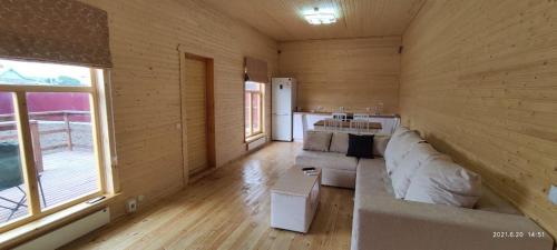 een woonkamer met een witte bank in een houten kamer bij ZHANUYA HOUSE in Borovoye